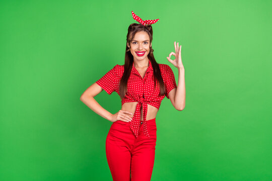 Photo portrait woman showing okay sign smiling in red outfit isolated vivid green color background