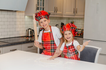 happy little children cooks Christmas cookies at home in kitchen in a chef costume. small blonde...
