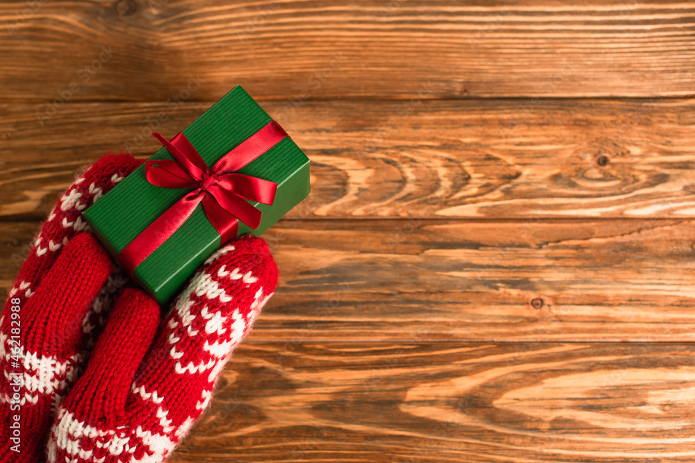 Canvas Prints cropped view of person in red mittens holding wrapped gift box above wooden surface