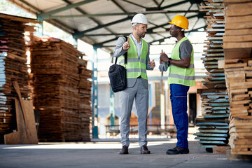 Warehouse inspector gives instructions to African American worker in lumber distribution department.