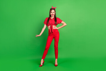 Photo of cheerful charming lady posing wear dotted blouse headband pants stilettos isolated green...