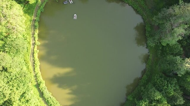 Aerial top view lake in forest. Drone slowly fly from  Parz lake (Parz lish) in Dilijan, Armenia. Summer time.  Famous, touristic, hiking place in Armenia. Boat in lake.