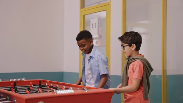 Children playing table football at break in school jumping for joy of winning. Middle school children playing foosball. Kids jumping for joy. Different kids playing together. High quality 4k footage