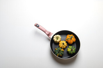 Decorative pumpkins on a pan over a white kitchen table background.Concept Of Thanksgiving Day, Halloween or Fall Harvest.