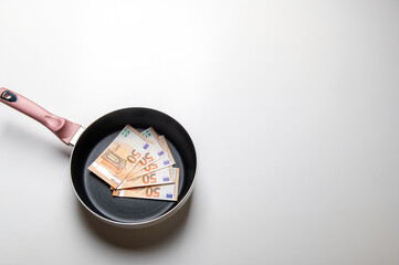 New frying pan with money euro banknotes on a white background.