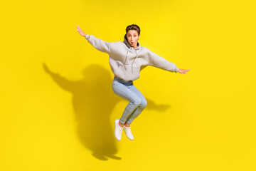 Fototapeta na wymiar Full length photo of cool brown hair young lady jump wear sweater jeans sneakers isolated on yellow background