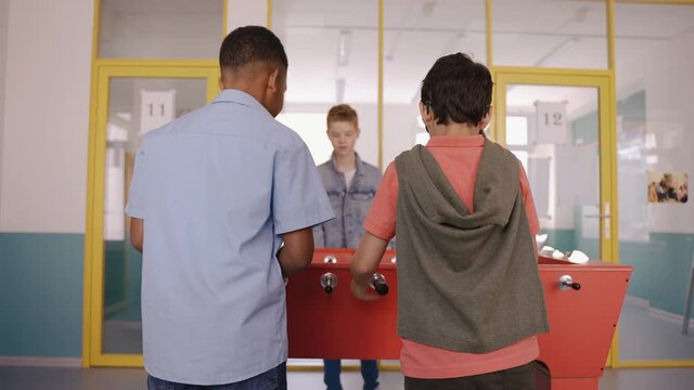 Children playing table football at break in school jumping for joy of winning. Middle school children playing foosball. Kids jumping for joy. Different kids playing together. High quality 4k footage