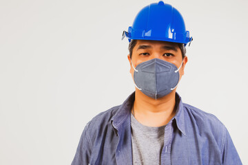 The handsome male worker wore a blue helmet and a dust mask to prevent PM2.5 and the epidemic COvid-19.