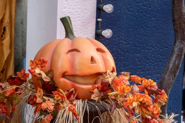 Foto op Plexiglas Halloween decoration. A smiling plastic Jack O lantern. Funny and cute pumpkin decorated with fall leaves outside of a store. Festive decorative lights ready for costume party celebration. © Stockwars