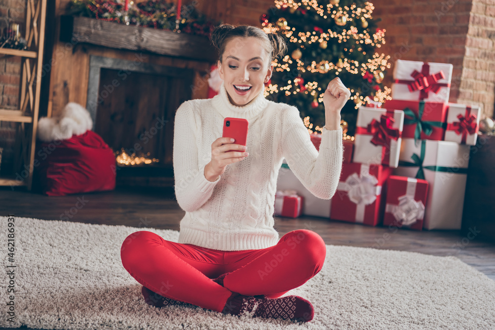 Poster Full body photo of young girl happy positive smile sit floor look read browse cellphone rejoice victory lucky noel indoors