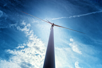 Wind power turbines in the countryside in a sunny day in agricultural field with blue sky and white clouds in summer