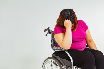Fat woman stressed about her weight : Obese asian woman is wheelchair-bound because she is overweight and unable to walk by herself due to her health problems and lack of exercise. - obrazy, fototapety, plakaty