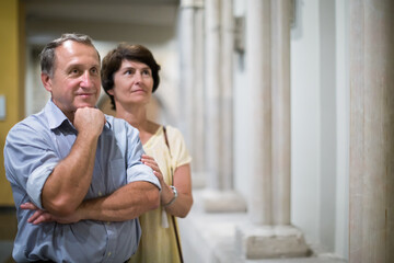 Naklejka premium mature couple turists examines the exhibit in museum