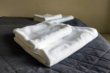 On the bed are clean white towels, hotel room.