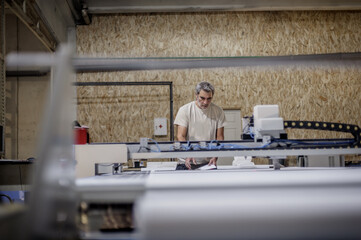 Technician works on CNC digital cutter machine for cutting textile