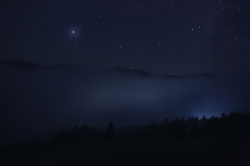 Fototapeta premium Picturesque view of night sky with beautiful stars over foggy hill