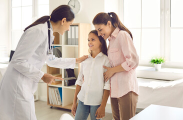 Mother and child seeing doctor together. Smiling pediatrician welcoming patient at her office. Friendly general practitioner talking to teen girl who came with her mom for health checkup to the clinic