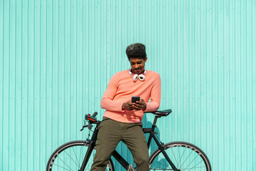 Mid adult man leaning on bicycle while using smart phone during sunny day