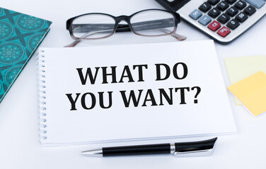 What Do You Want question text quote on white notebook on office desk