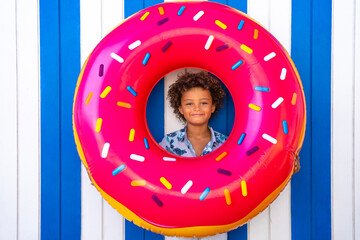 Cute smiling boy looking through inflatable doughnut