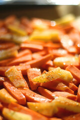 Slices of potato and sweet potato, seasoned with various spices, herbs and olive oil, ready for oven. Selective focus.