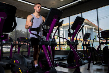 Athlete young man in sportswear doing fitness exercises on xercising on the xtrainer machines  in the gym. Healthy lifestyle motivation