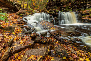 flowing silky cascading waters with  colorful autumn foliage background  on the  woods in Ricketts Glen Pennsylvania