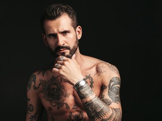 Portrait of handsome confident stylish hipster lambersexual model. Sexy modern man. Naked torso with tattoos.Fashion male posing in studio on dark background