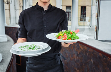 Waiters carrying plates with food, in a restaurant.