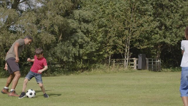 Tracking Shot of Adult Playing Football with Group of Children 02