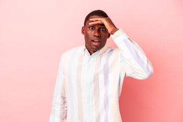 Young African American man isolated on pink background looking far away keeping hand on forehead.