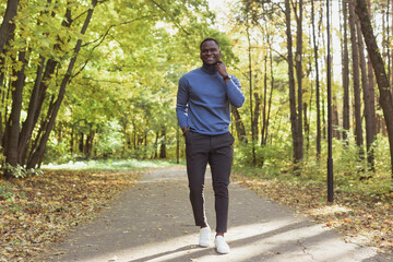 Fototapeta premium African american student walking in the park in autumn season