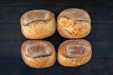 Artisan wheat bread lies on the surface of a dark color, background, top view.