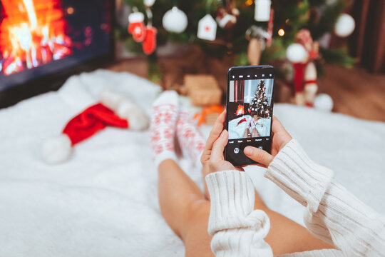woman taking picture on the phone near christmas tree