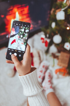 woman taking picture on the phone near christmas tree