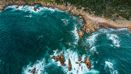 
Island coastline with powerful waves breaks on the rocks, early in the morning. Aerial view over the mediterane ocean water at the steep cliffs. Drone shot Italy