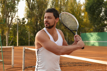 Handsome man playing tennis on court outdoors