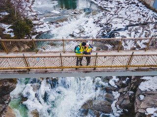 couple travelers on the bridge across waterfall