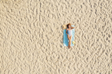 Woman sunbathing on beach towel at sandy coast, aerial view. Space for text - obrazy, fototapety, plakaty