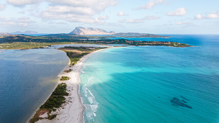 famous La Cinta beach overlooking the island of Tavolara. white sandy beach and soft blue water. very popular with tourists, kiters, great for a romantic walk. drone aerial view, Sardinia Italy.