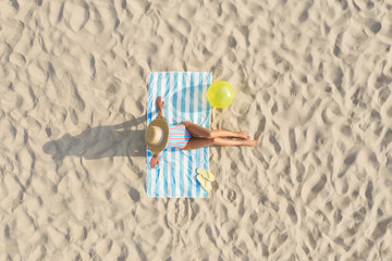 Woman sunbathing on beach towel at sandy coast, aerial view