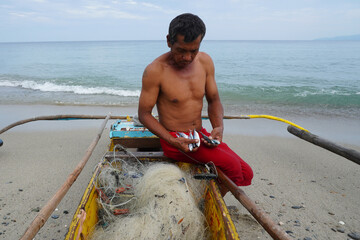 Traditional Philipine fisherman unhappy with his night fishing. Unsustainable lifestyle. A few small fish after working-fishing all night.  Few fish so no money. and no future