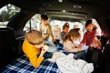 Mother with four kids at vehicle interior. Children in trunk. Traveling by car, lying and having fun, atmosphere concept.