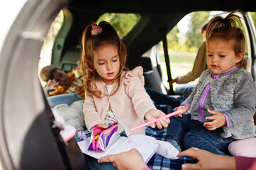 Mother with four kids at vehicle interior. Children in trunk. Traveling by car, lying and having fun, atmosphere concept.