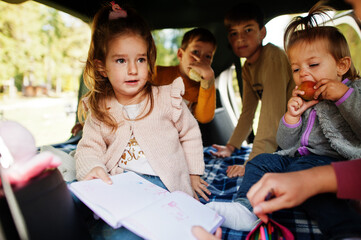 Mother with four kids at vehicle interior. Children in trunk. Traveling by car, lying and having fun, atmosphere concept.
