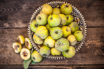 Quince fruits on a wooden background. Harvest of autumn fruits. Yellow tart hard fruit. Cut apple-quince with leaf. Terry grade. Healthy vitamin food.