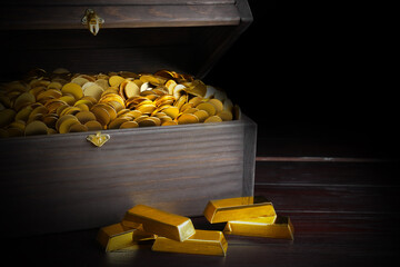 Open treasure chest with coins and gold bars on wooden table, closeup