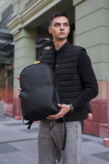 Man holding leather backpack in a city