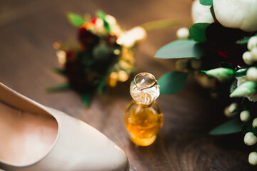 Pair of elegant and stylish bridal shoes with wedding rings and a bouquet of roses and other flowers