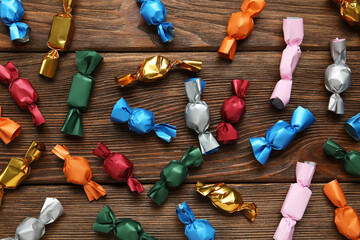 Many candies in colorful wrappers on wooden table, flat lay